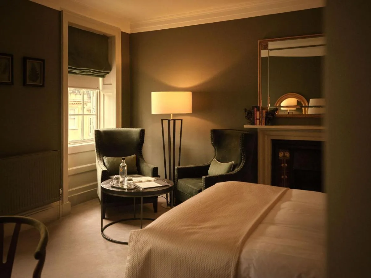 A bedroom with a bed, two chairs and a lamp at The Queensberry Hotel in Bath